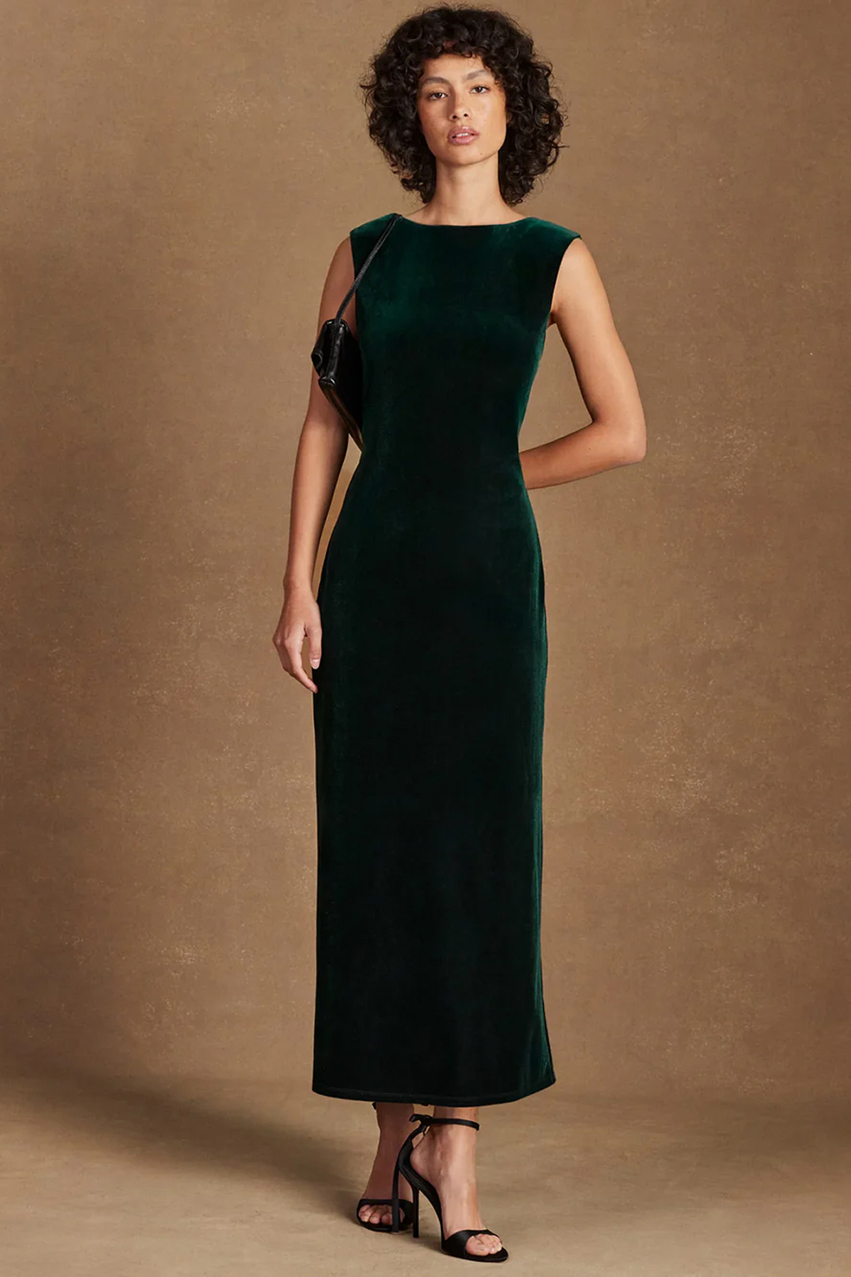 Model wearing a petite emerald-green velvet maxi dress with a boat neckline and fitted column shape.