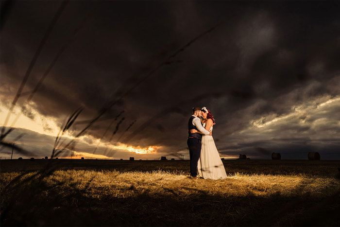 couple in field at night with a full moon behind them