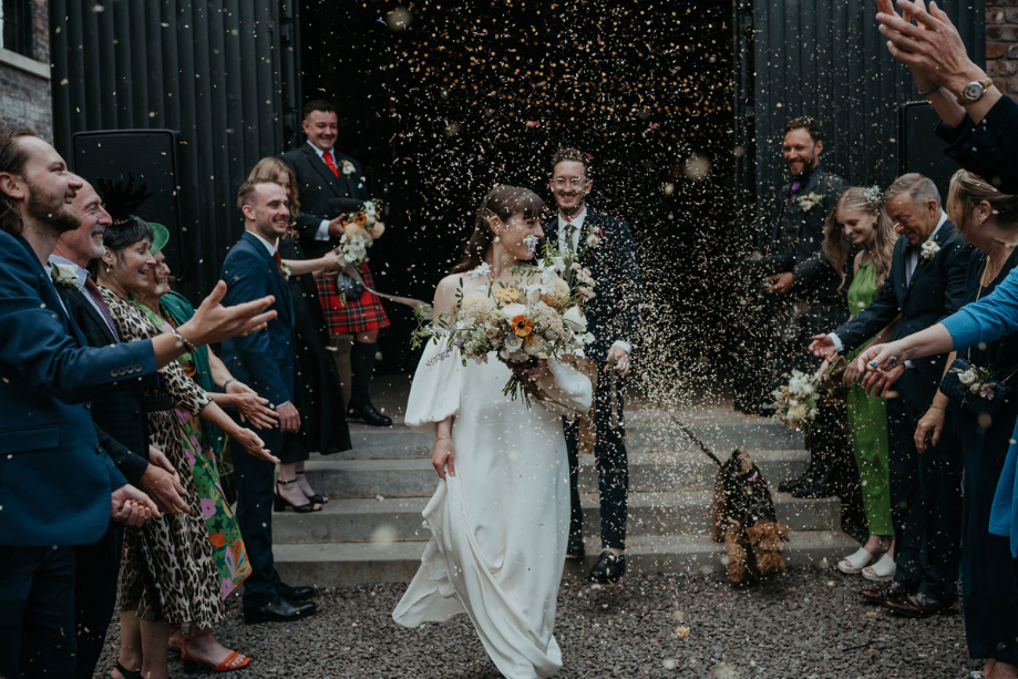 Confetti thrown at happy couple as they walk out their venue with their dog