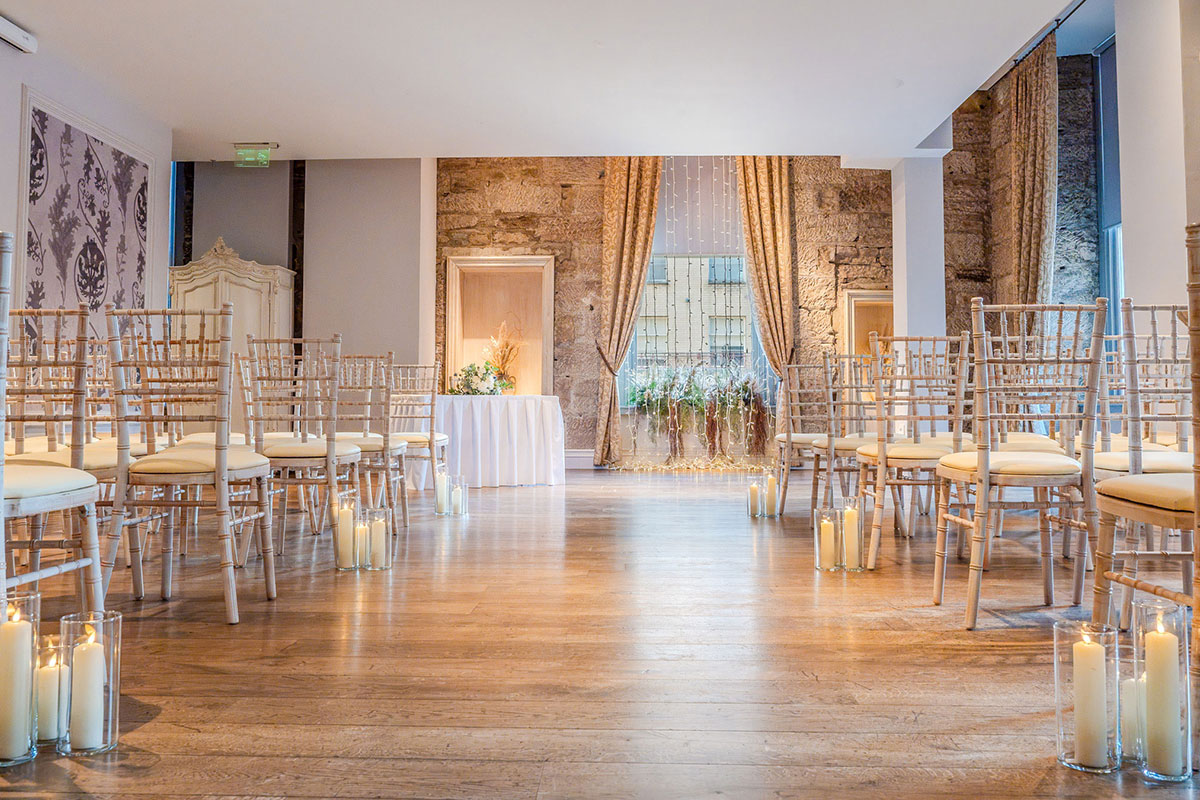 wedding ceremony set up at citation in glasgow with wooden flooring, candles and cross backed chairs