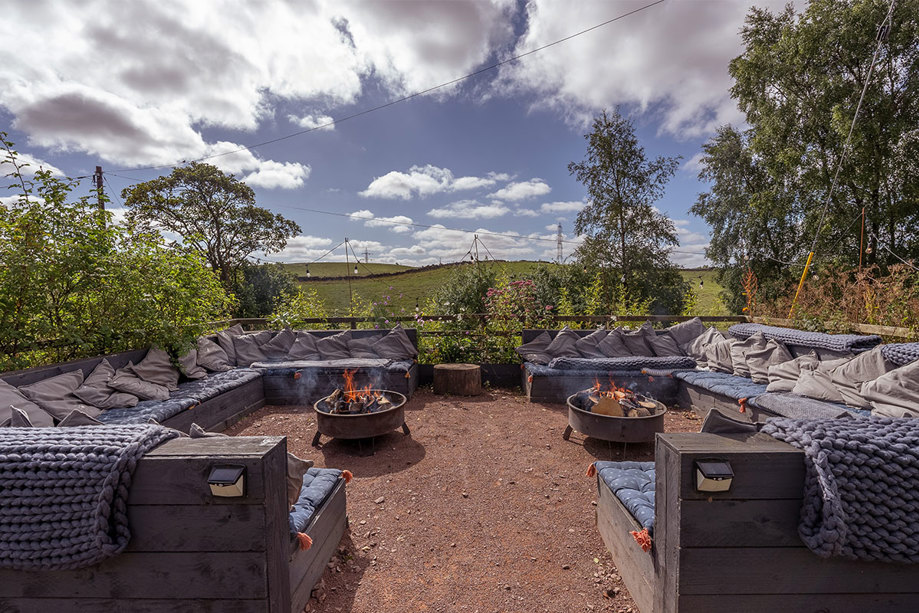 An area with two firepits and outdoor seating wrapped around them