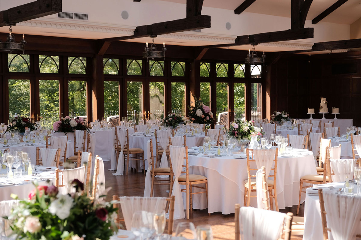 ballroom set up for wedding dinner with wooden chairs and cream linen at crossbasket castle