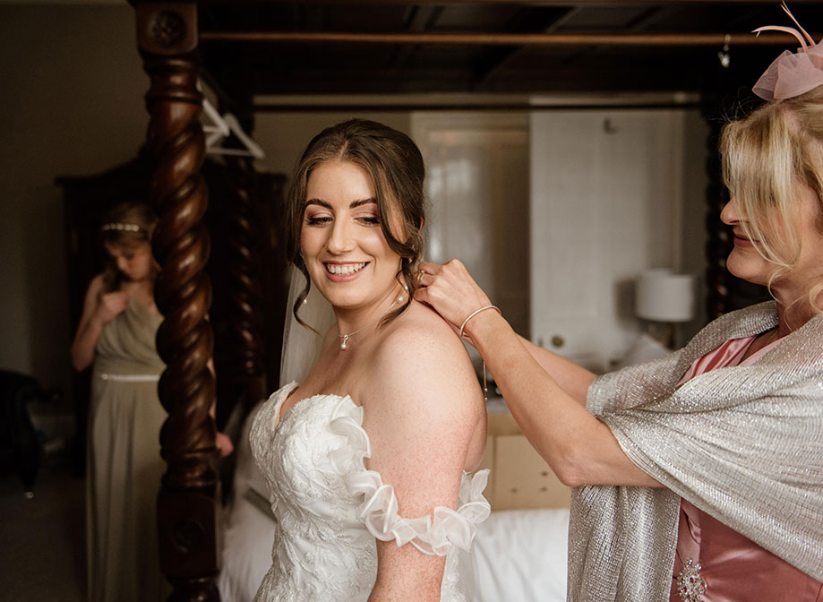 woman putting a necklace on a younger woman who is standing in front of her