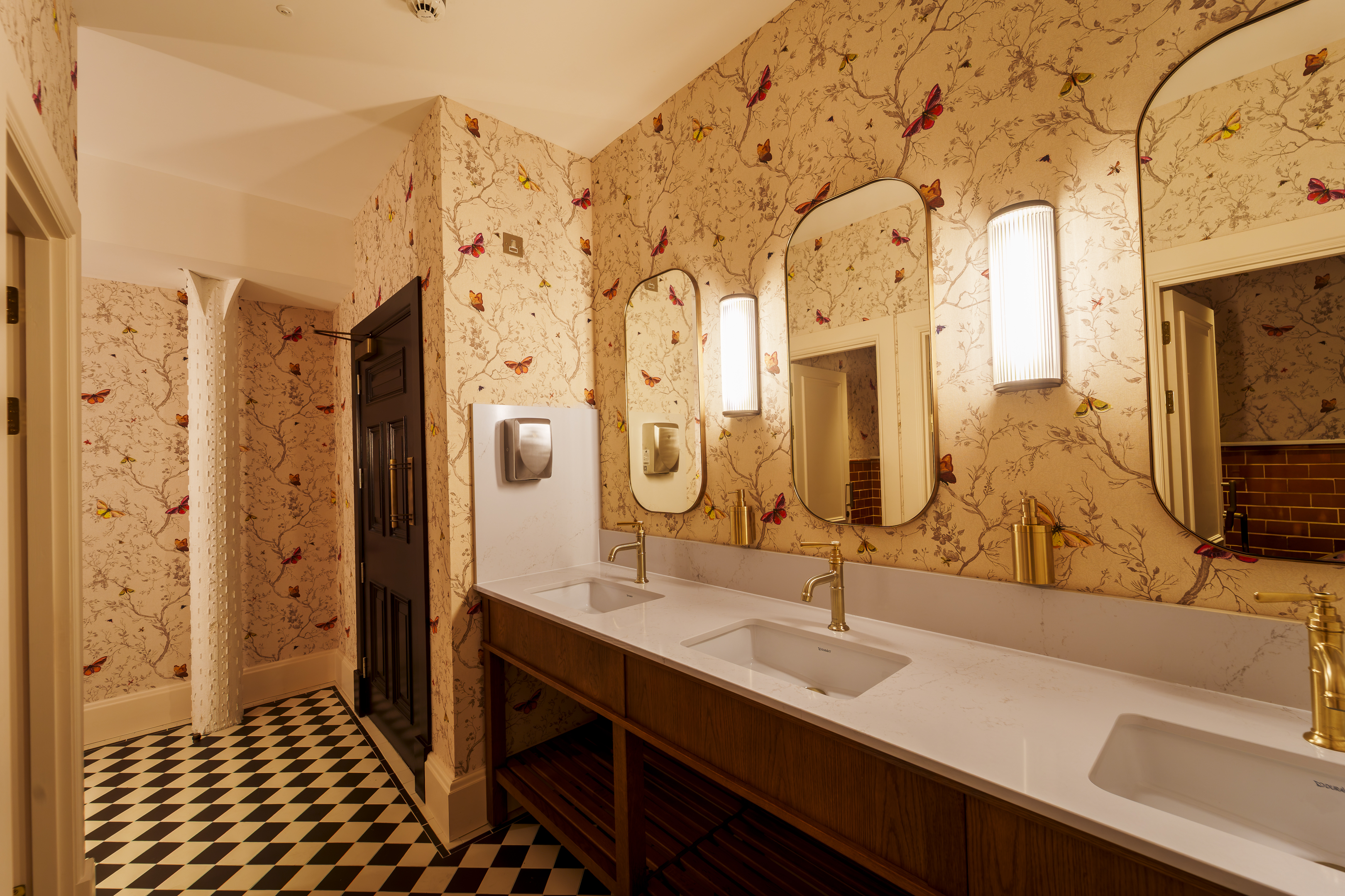 the bathrooms at the collector's hall with checkerboard flooring and large gold mirrors