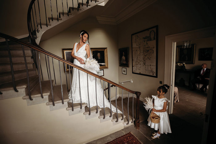 A Bride Standing On A Staircase Looking Down To A Young Girl Wearing A White Dress