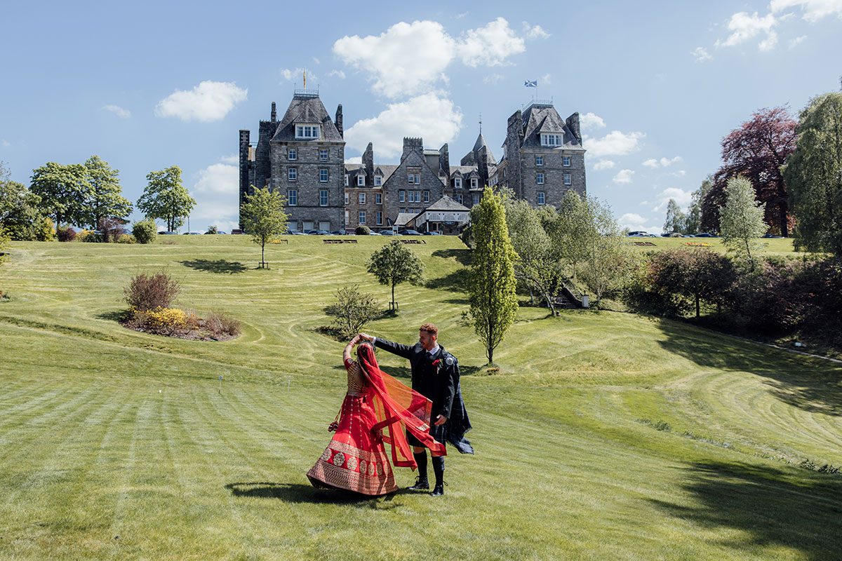 Bride and groom dancing on the lawn with Atholl Palace Hotel in the background during their wedding portraits