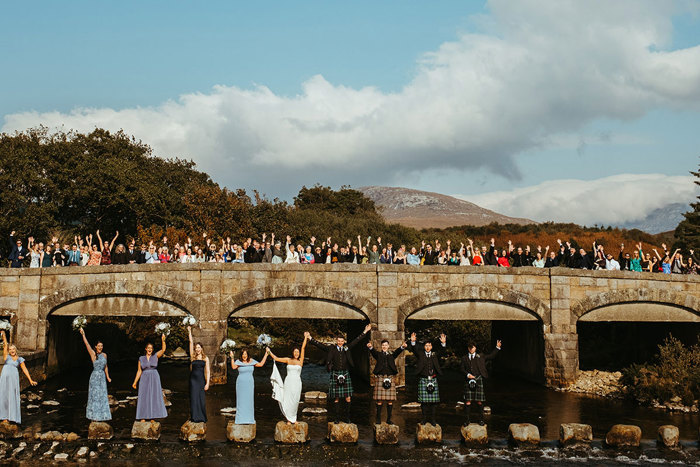 guests stand on dougarie boathouse bridge and stepping stones during wedding