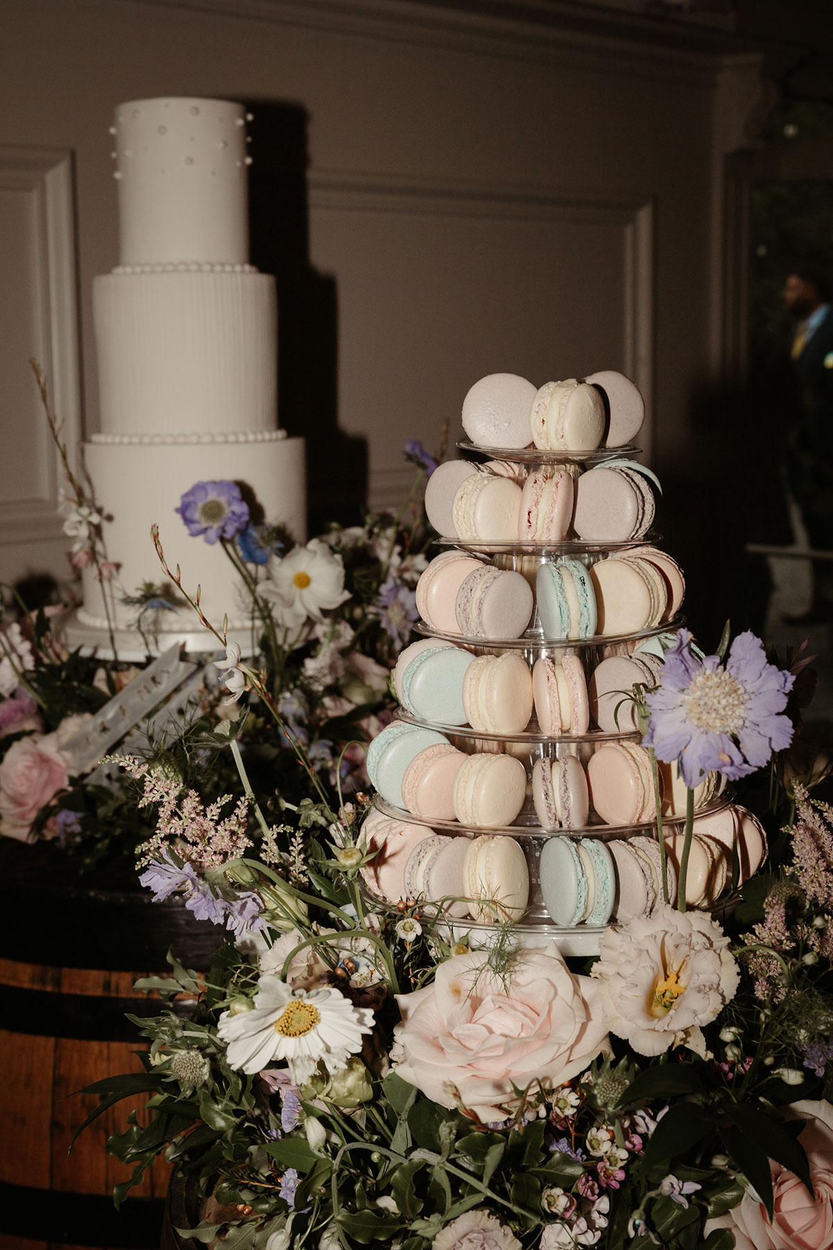 pastel macaron tower and pastel wedding flowers with ivory cake in background