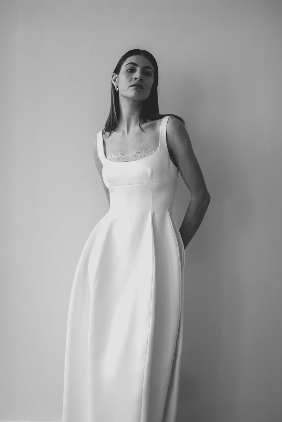 black and white image of a dark haired model wearing a structured wedding dress with lace peeking out of the bodice