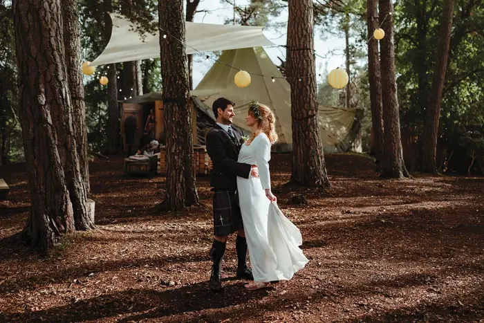 A bride and groom looking lovingly at each other standing in a forest