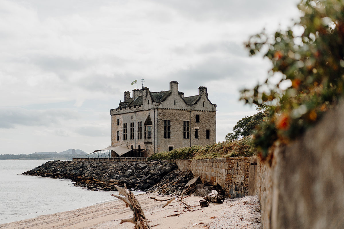 view from sandy beach of exterior of Barnbougle Castle near Edinburgh
