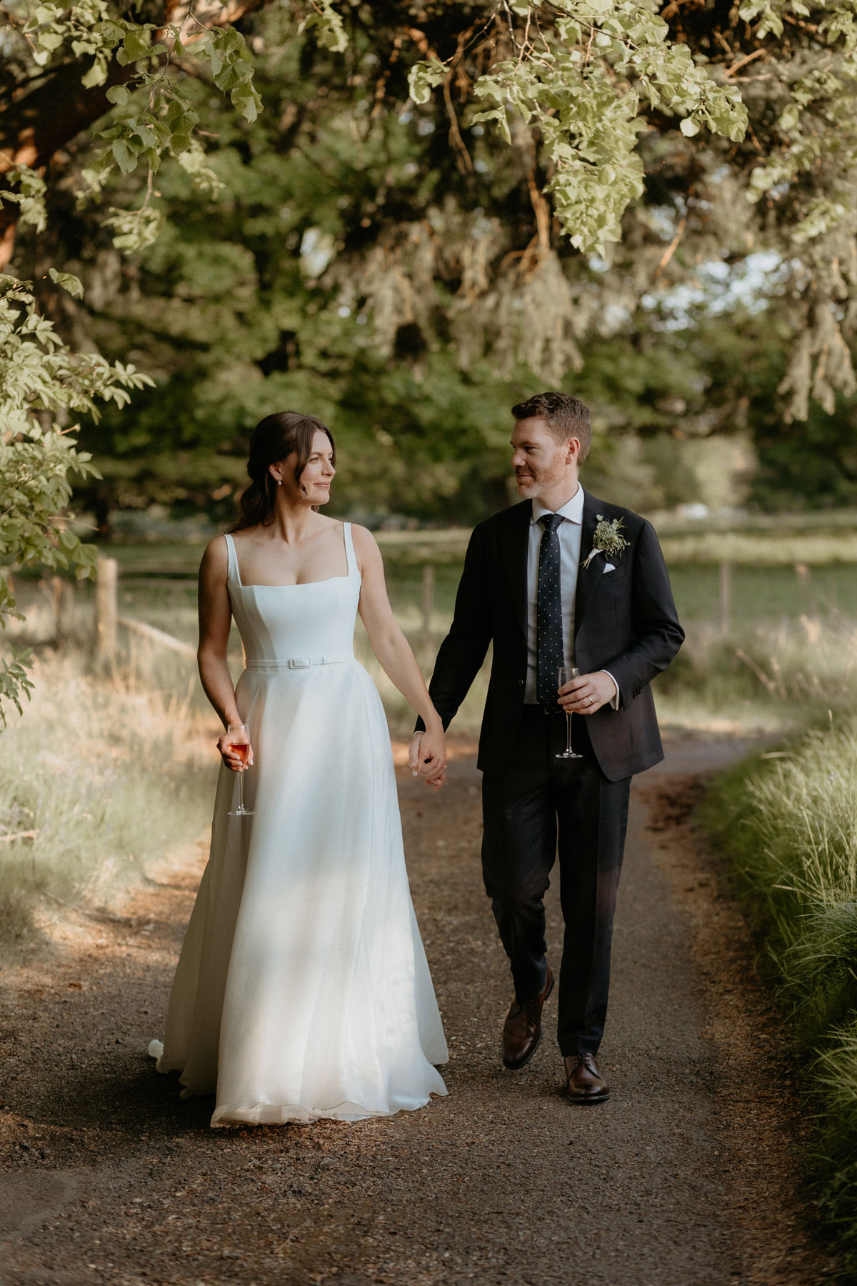 Bride and groom walking hand in hand through the grounds of The Byre at Inchyra in Perthshire.