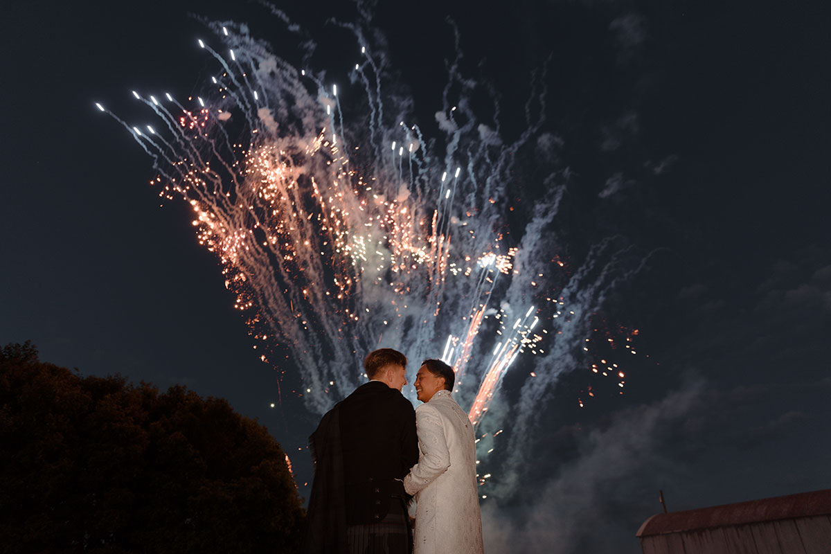 Fireworks finale behind the grooms at their outdoor Falkirk farm wedding evening celebration