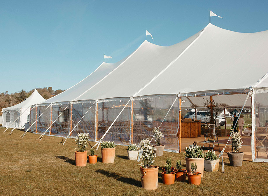 a wedding marquee with clear plastic panels and potted plants at entrance