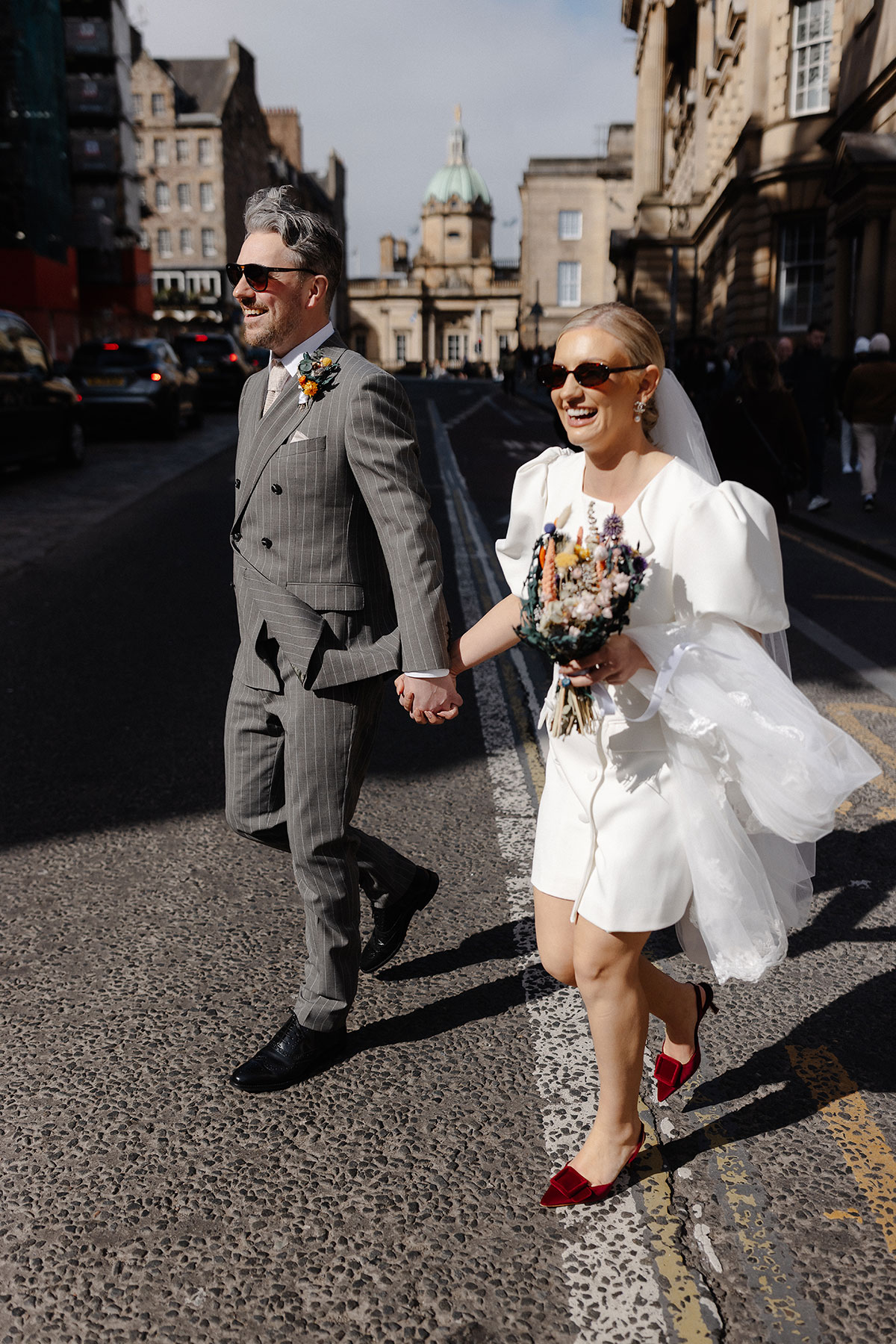Bride and groom walk hand-in-hand through Edinburgh’s Old Town streets after their registry office wedding at City Chambers.