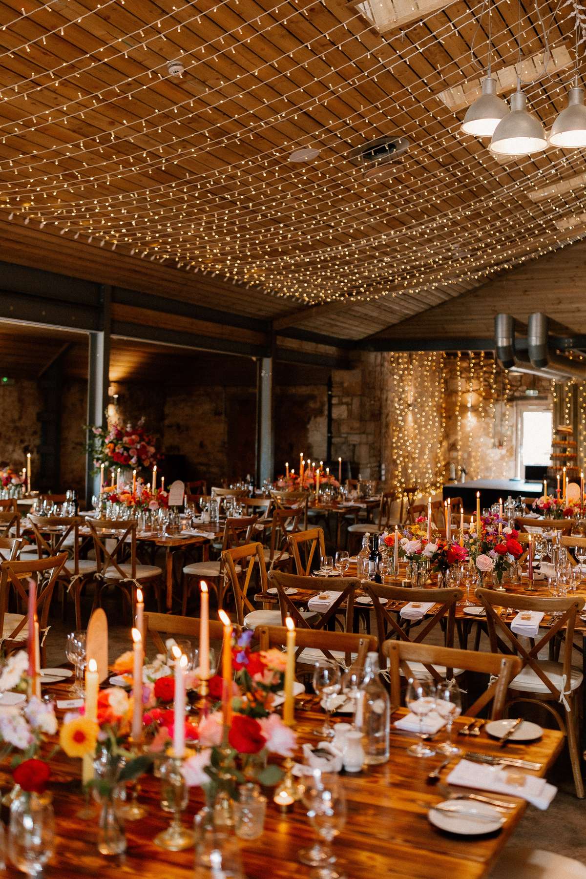 Elegant wedding breakfast styling at Falside Mill featuring candlelit tables and vibrant floral centrepieces