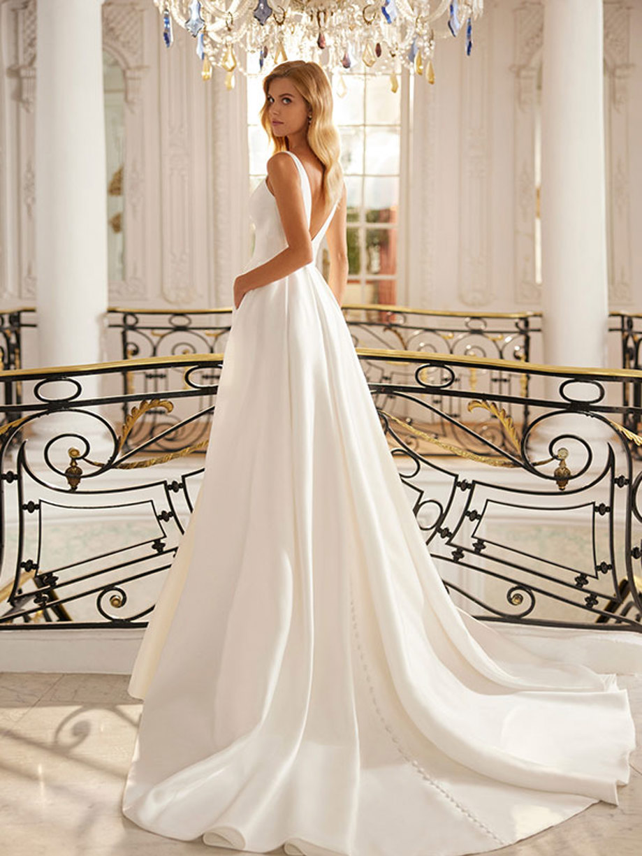 view from the back of a woman wearing a v-back wedding dress with buttons trailing down the centre back of skirt