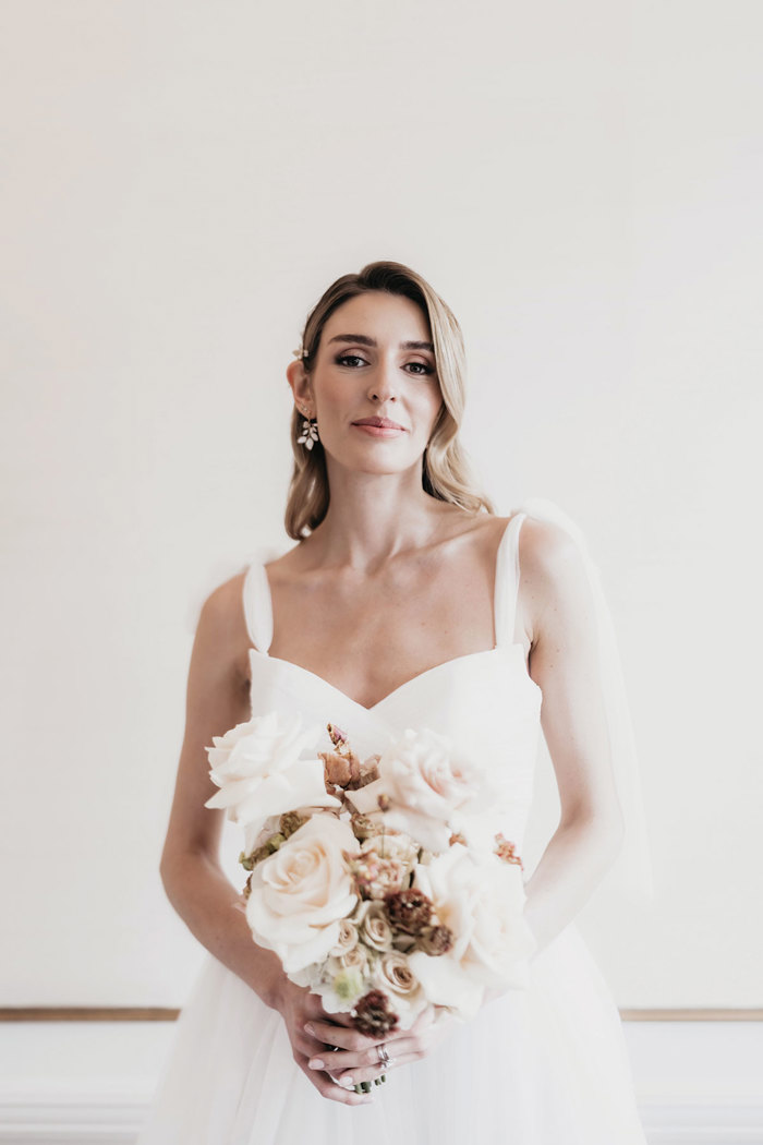 a bride wearing a wedding dress from Kudos Bridal Dunfermline holding a bouquet of peach roses and assorted flowers