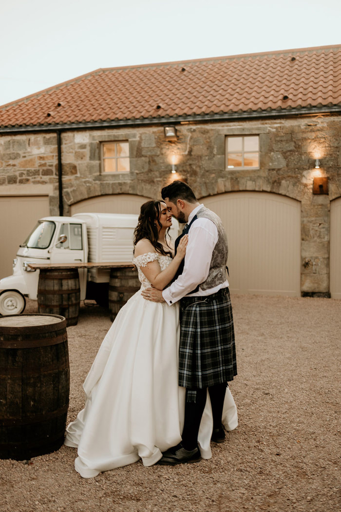 couple stand outside of building at wedding at falside mill