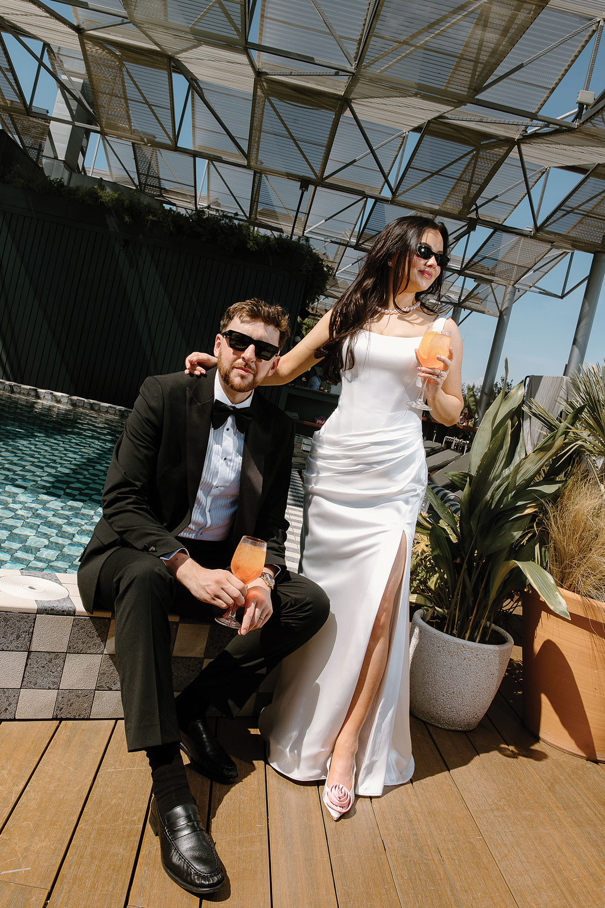 Bride and groom relaxing by a rooftop pool with cocktails during their destination wedding celebration in Barcelona