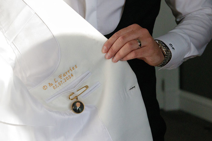 a look at yellow-gold name and dates embroidered inside the lining of a white suit jacket