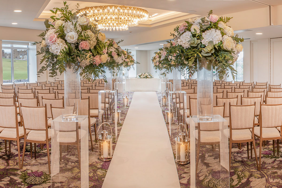 Wedding ceremony aisle at Old Course Hotel in St Andrews with floral pillars and golf course views