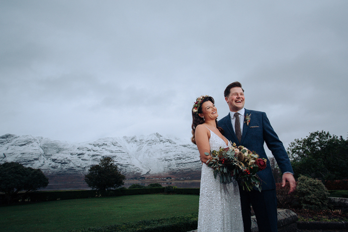 Bride and groom smile in front of snow-capped mountain