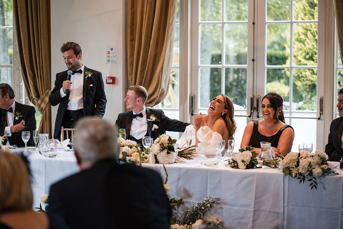 Bride and groom laugh at top table during best mans speech