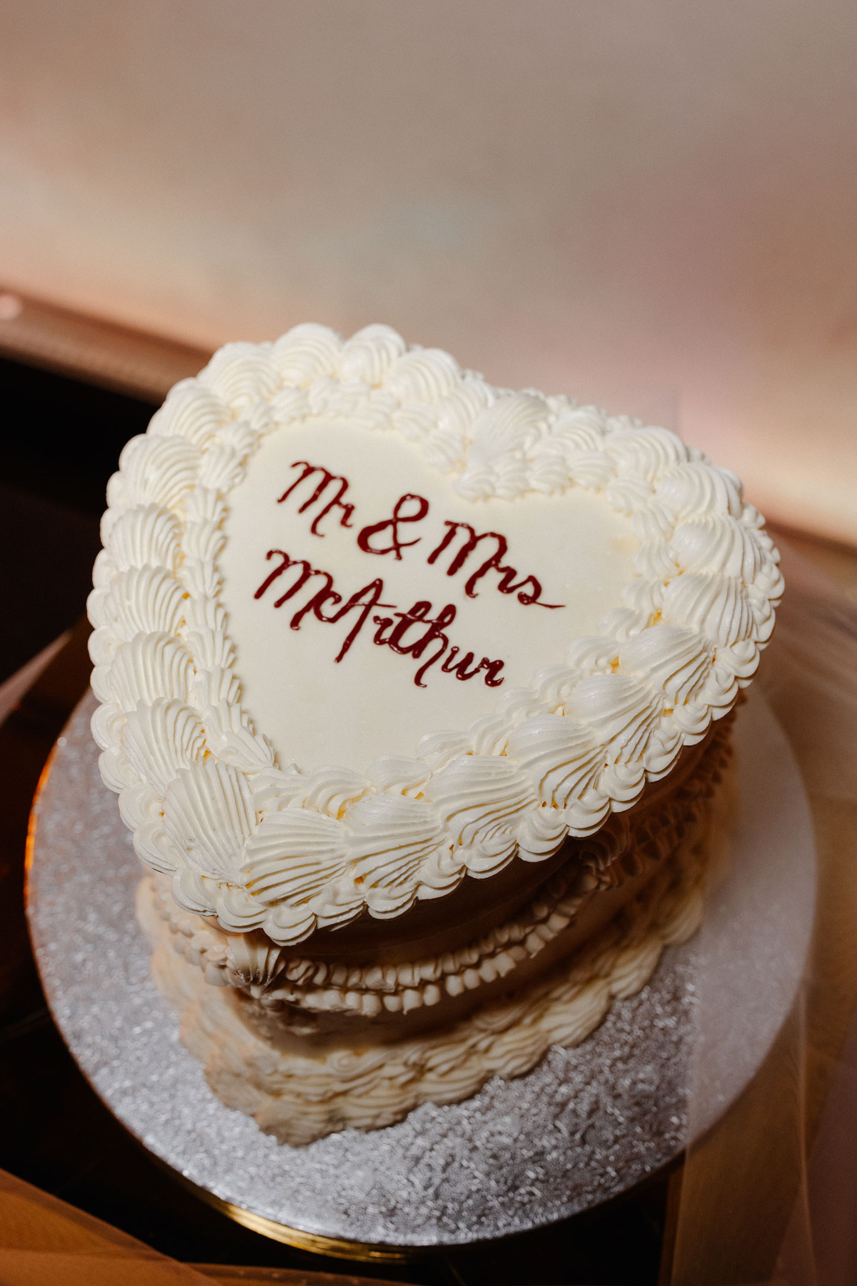 Vintage-inspired heart-shaped wedding cake iced in white with ‘Mr & Mrs McArthur’ piped on top, photographed at Virgin Hotels Edinburgh.