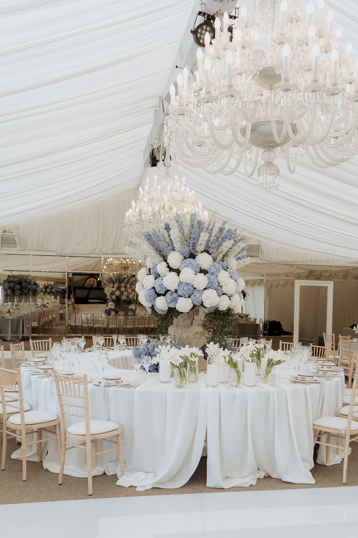 Blue and white hydrangea wedding centrepiece beneath crystal chandeliers at Carlowrie Castle wedding reception