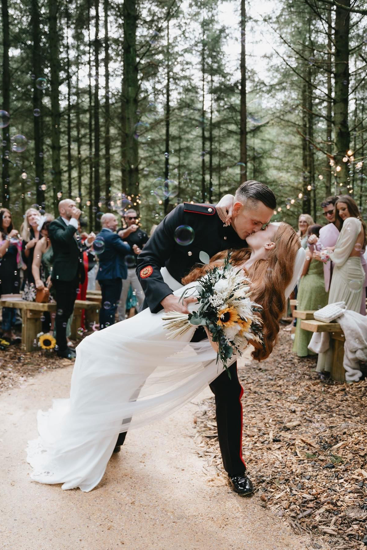Newlywed couple kissing in a woodland ceremony area at Eden Leisure Village outdoor wedding venue.