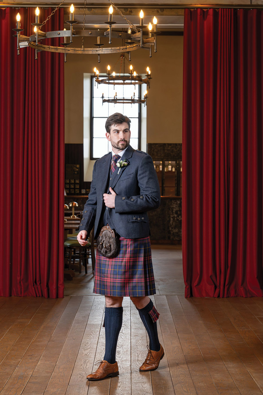 a man in a Slanj Kilts kilt walking across a wooden floor in the Hay Loft at Rosebery Steading