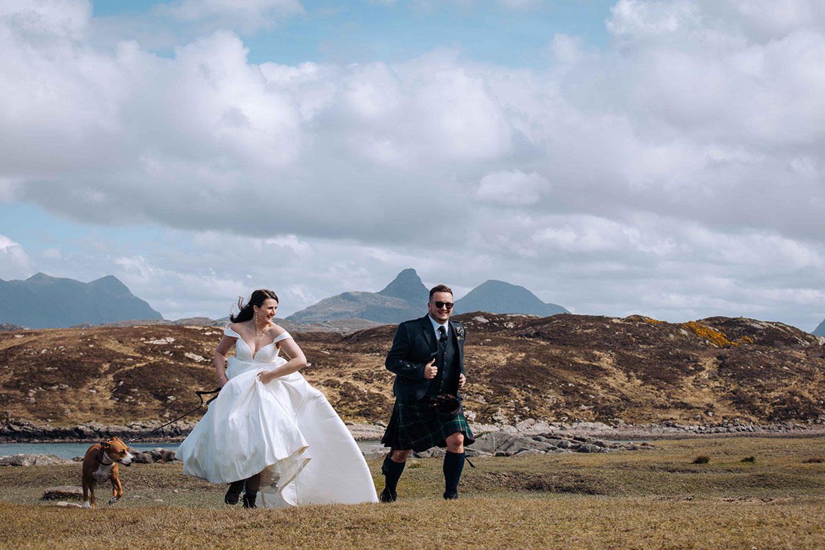 Bride and groom with their dog running on coastal land at Achnahaird Bay.