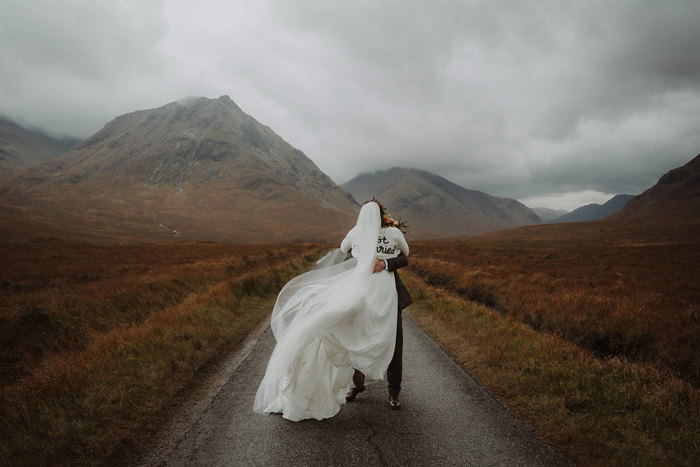 a bride and groom kissing in Glencoe surrounded by mountains