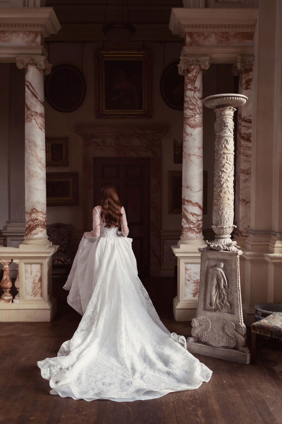 Back view of a bridal gown with a long train framed by marble columns at Gosford House.