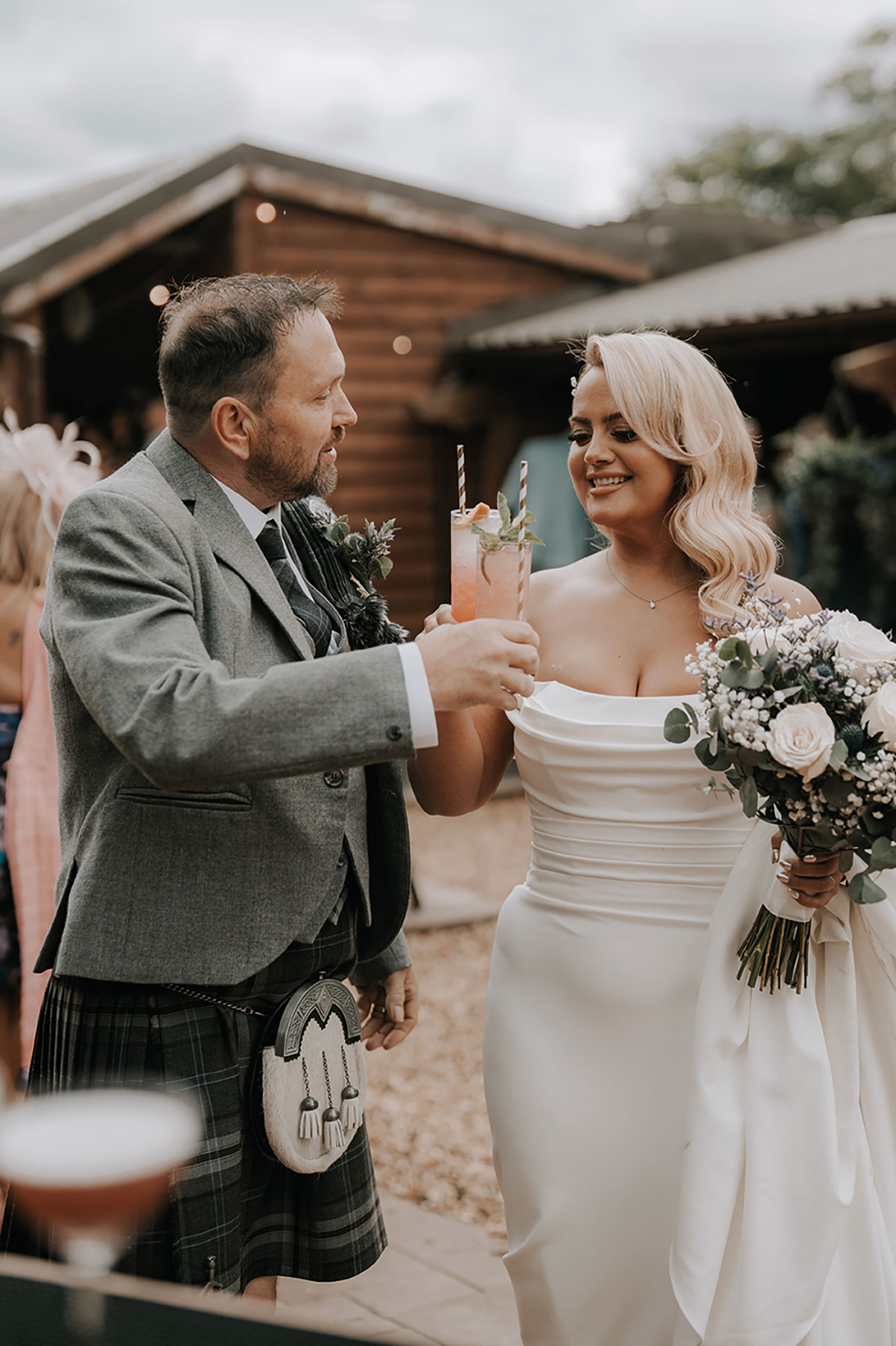Bride and groom raise cocktails together during the outdoor drinks reception.
