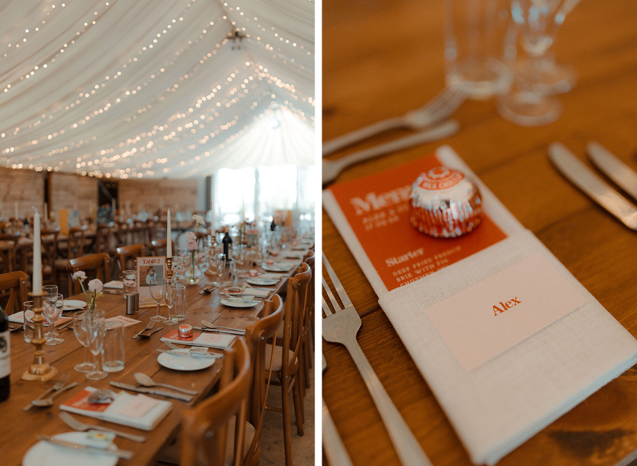 Draped canvas ceiling with rows of fairy lights illuminating a long wooden table wedding reception set up at Cow Shed Crail on left. A Tunnocks tea cake sits on an orange wedding menu and place name setting on a wooden table at a wedding.