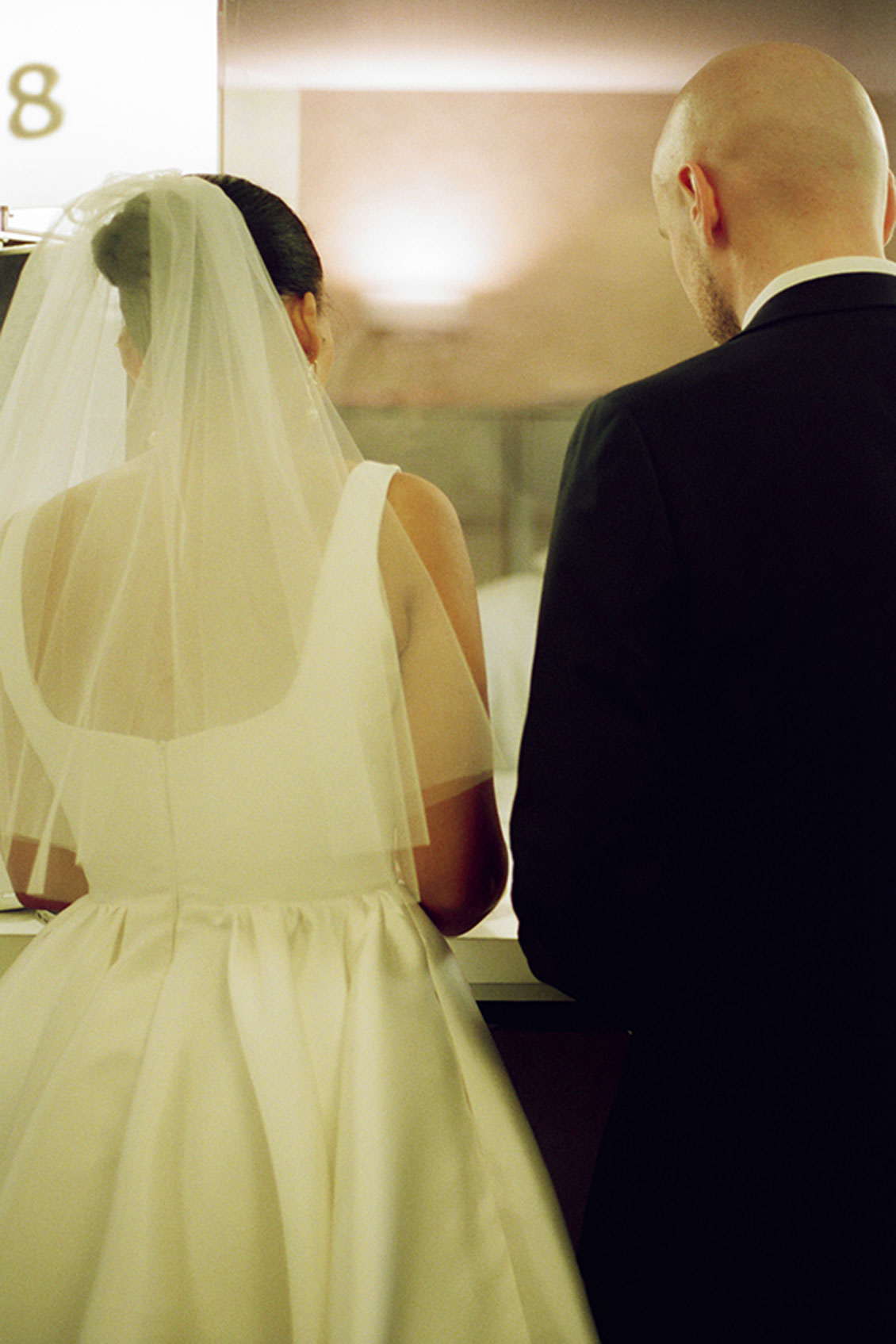 Bride and groom at New York City Hall counter during elopement ceremony paperwork