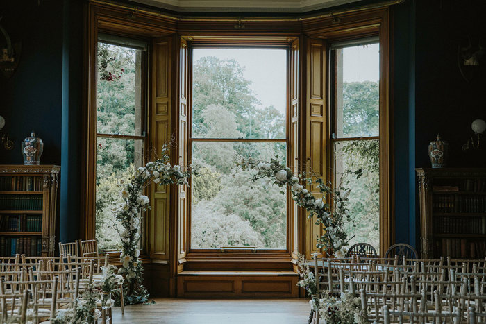 detail shot of ceremony room with wooden chairs and floral arch for wedding inside at cambo house