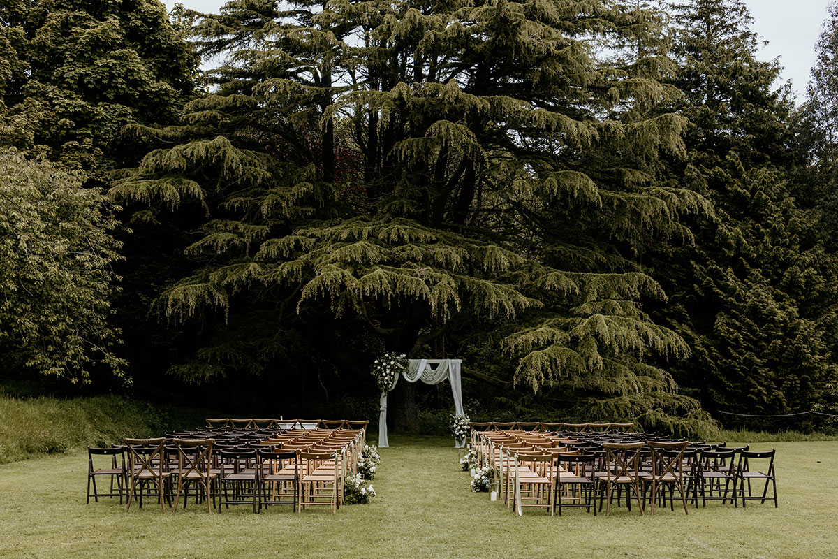 Outdoor wedding ceremony setup on the lawn at Cambo Estate with chairs and floral arch in Fife