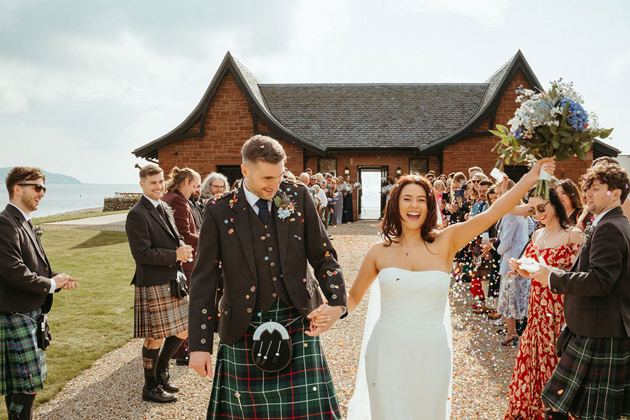 guests throw confetti over bride and groom during wedding at dougarie boathouse