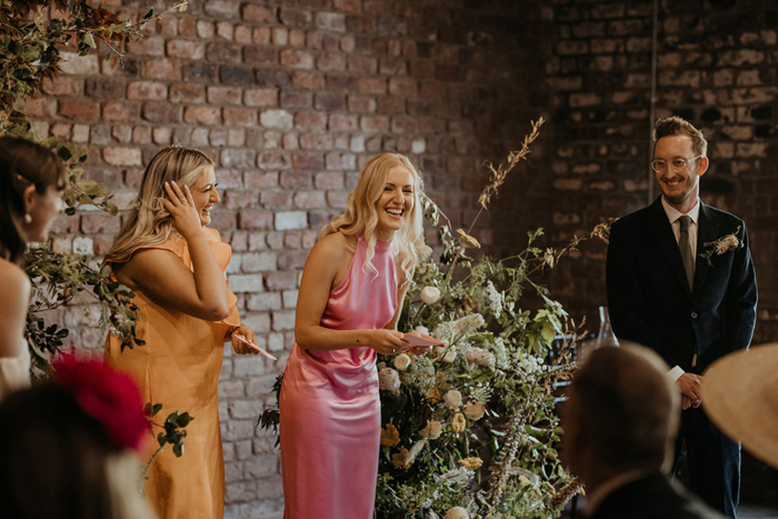 Bridesmaids wearing pink and orange dresses do readings at the ceremony