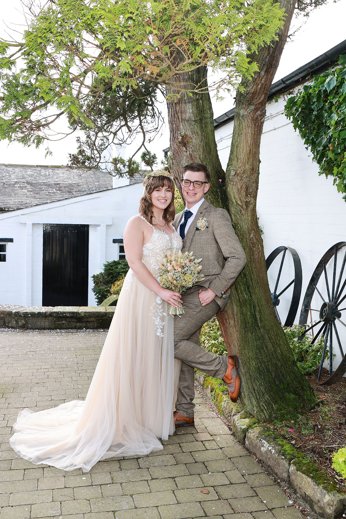 bride and groom lean against tree on wedding day at gretna green
