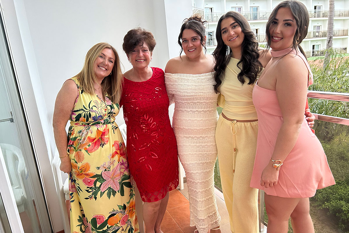 a group of women standing on a balcony posing for a photo