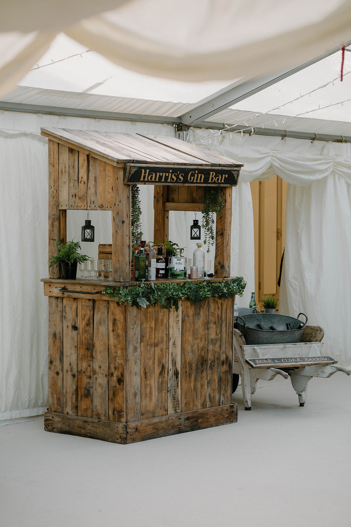 Rustic wooden gin bar inside a wedding marquee at Cluny Castle, an exclusive-use Aberdeenshire wedding venue.