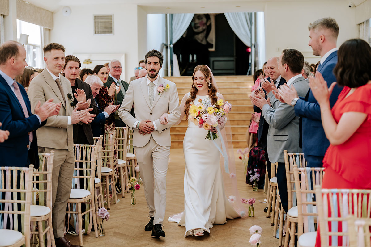 a bride walking down the aisle with her brother during at the start of a carlowrie castle wedding ceremony