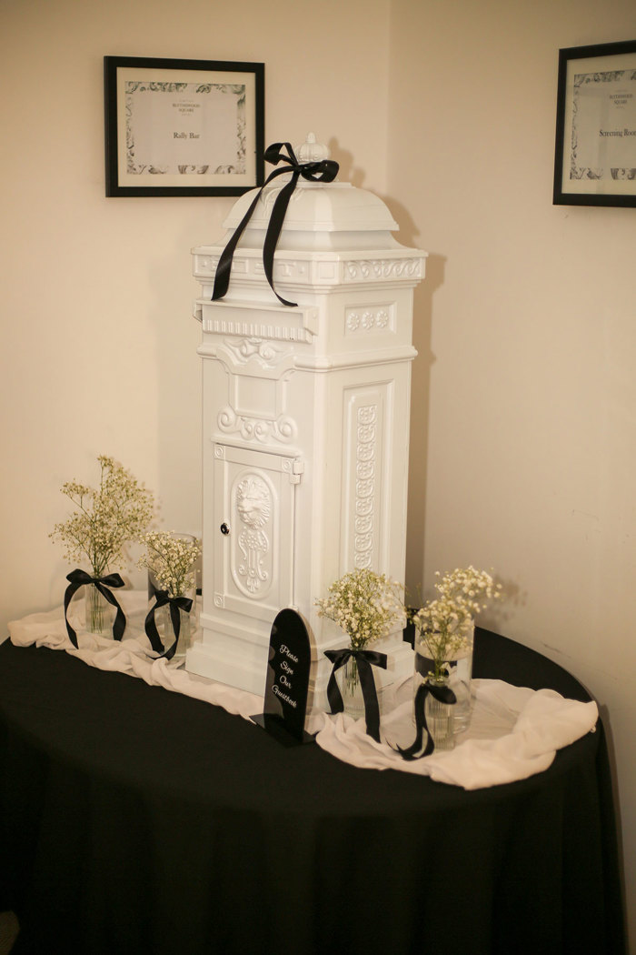 white postbox for wedding guests sit on top of table with black linen and flowers next to it