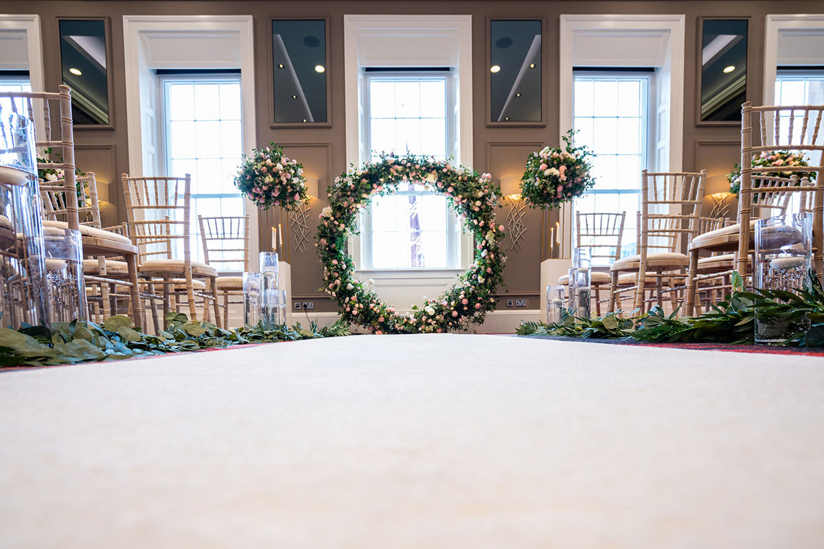 Wedding ceremony setup in the Custom House Ballroom at Clayton Hotel Glasgow with floral arch and aisle décor.