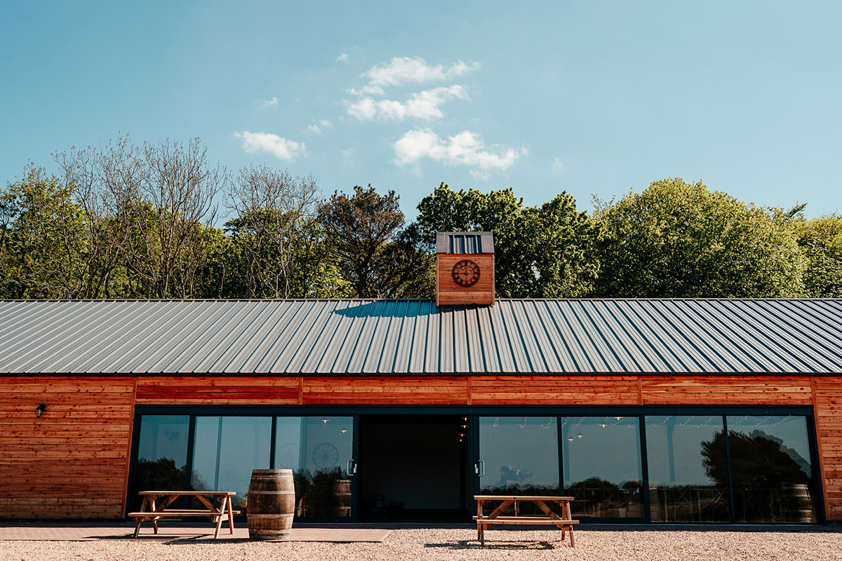 Wooden reception barn exterior at Harvest Moon Weddings in East Lothian with picnic benches and countryside surroundings.