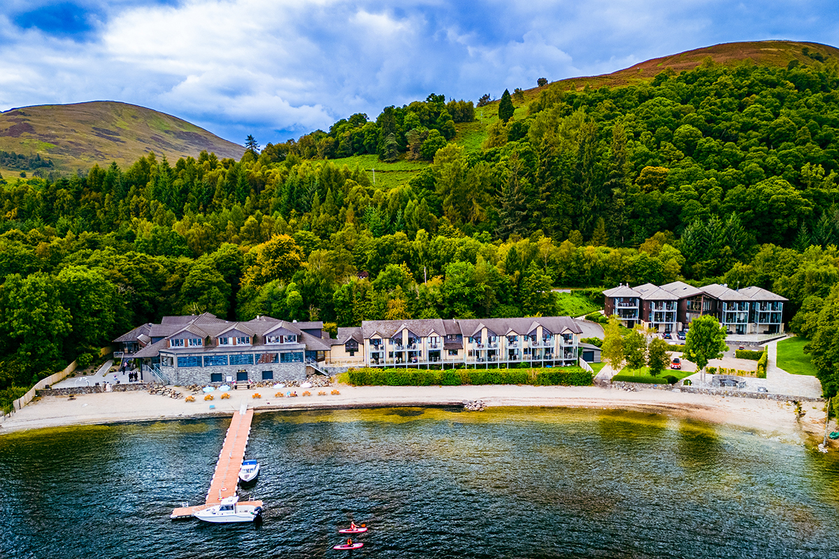 overhead view of waterside venue with dock and boats and plenty of green forestry behind it